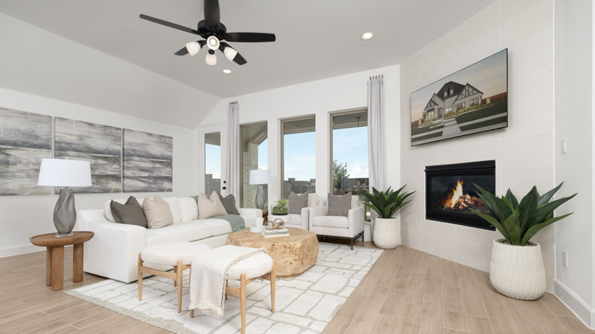 Living room with white sectional sofa, stone-look fireplace, and wall-mounted TV.