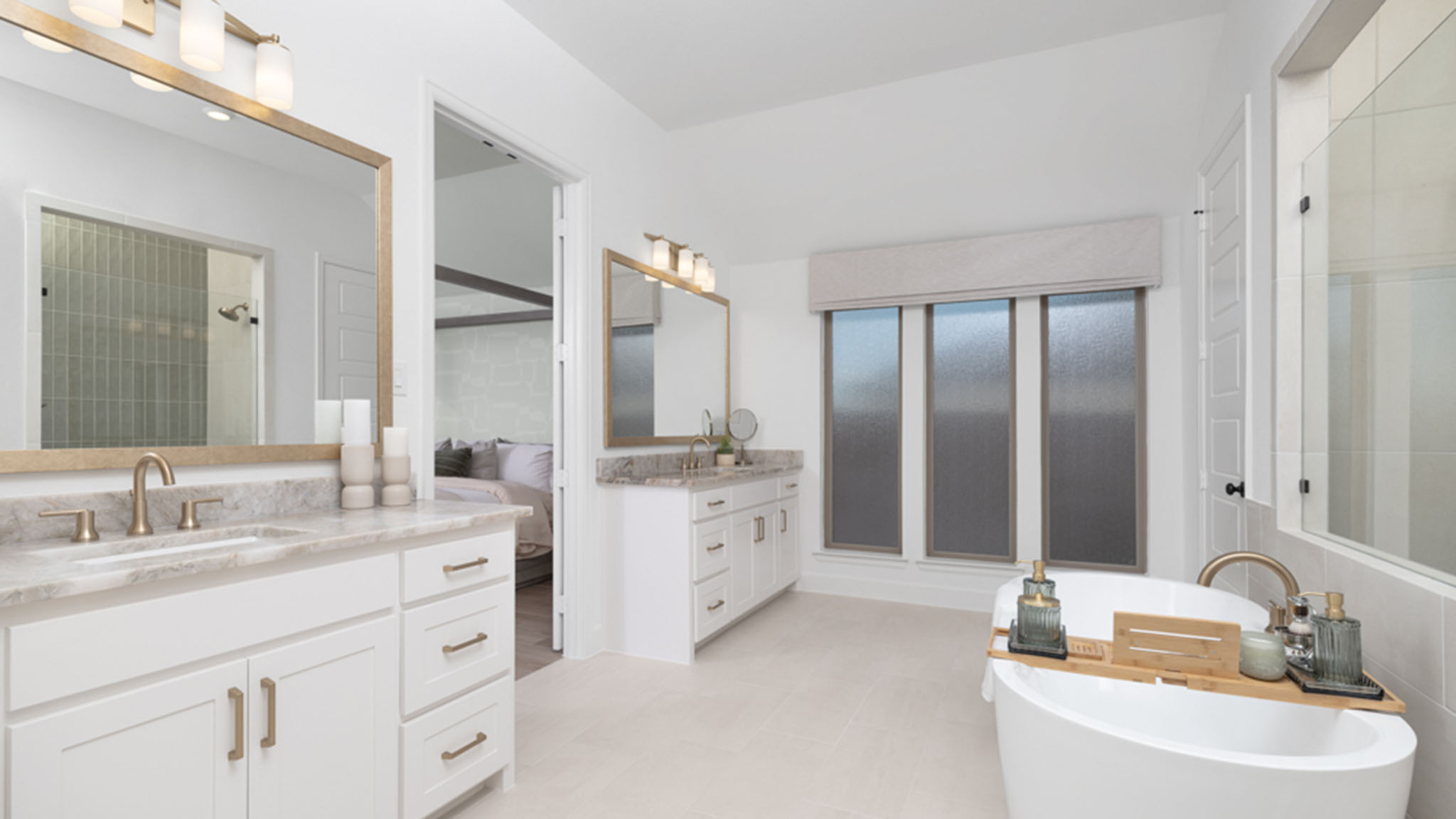 Primary bathroom with dual vanities, gold-framed mirrors, and freestanding soaking tub.