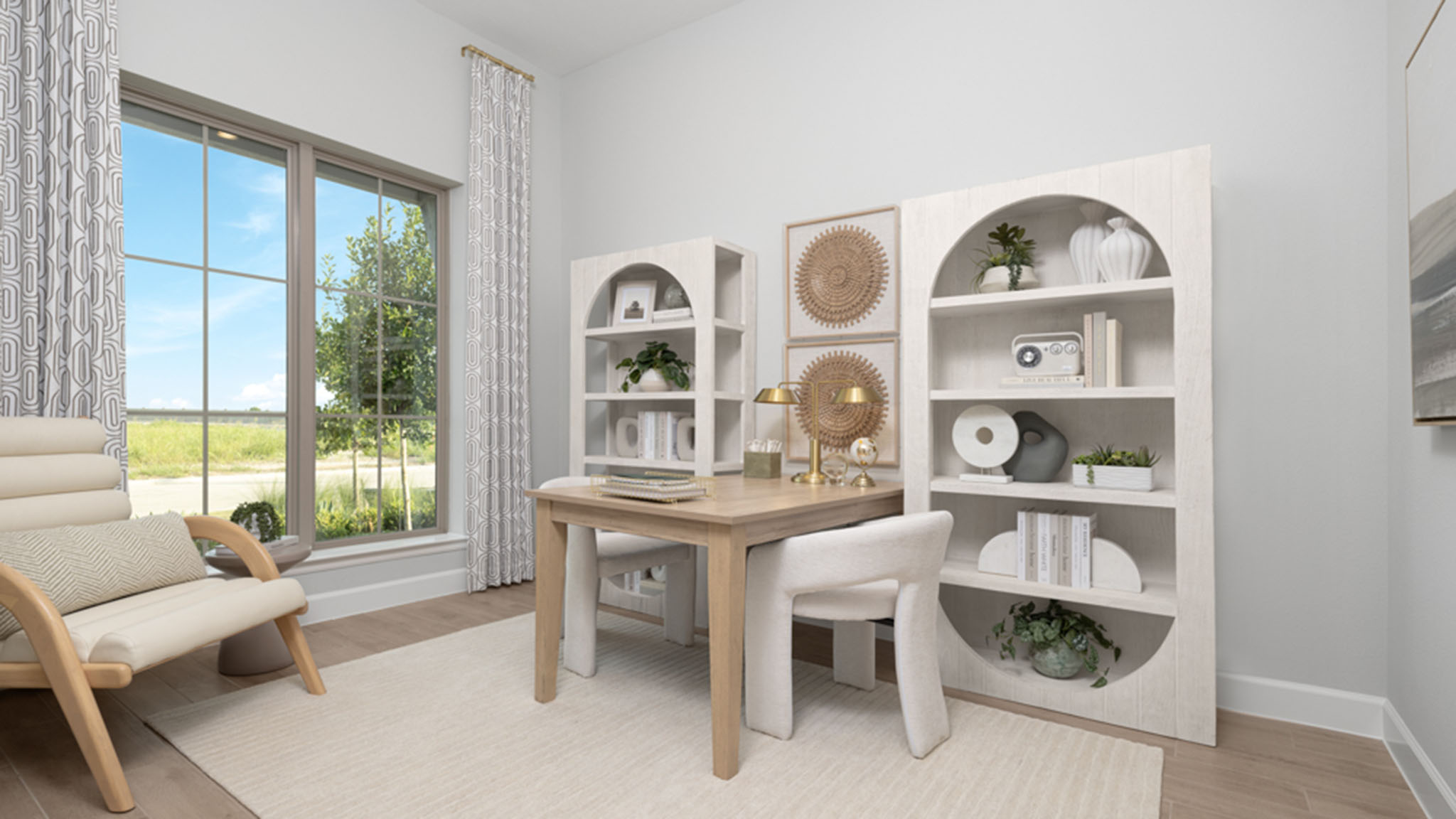 Home office with wood desk, cream chairs, and arched built-in bookshelves.