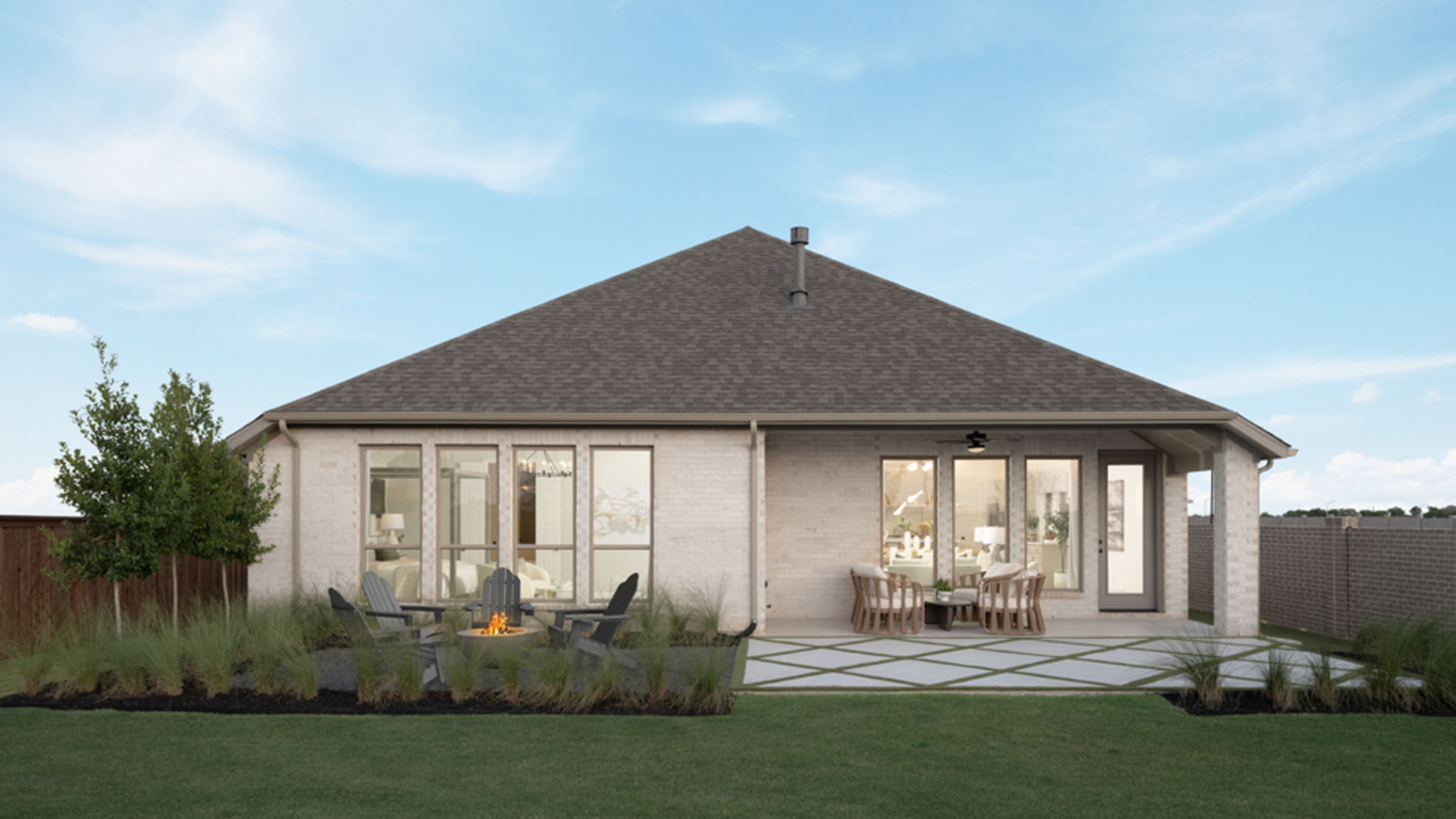 Rear exterior of a one-story brick home with covered patio and outdoor seating at dusk.