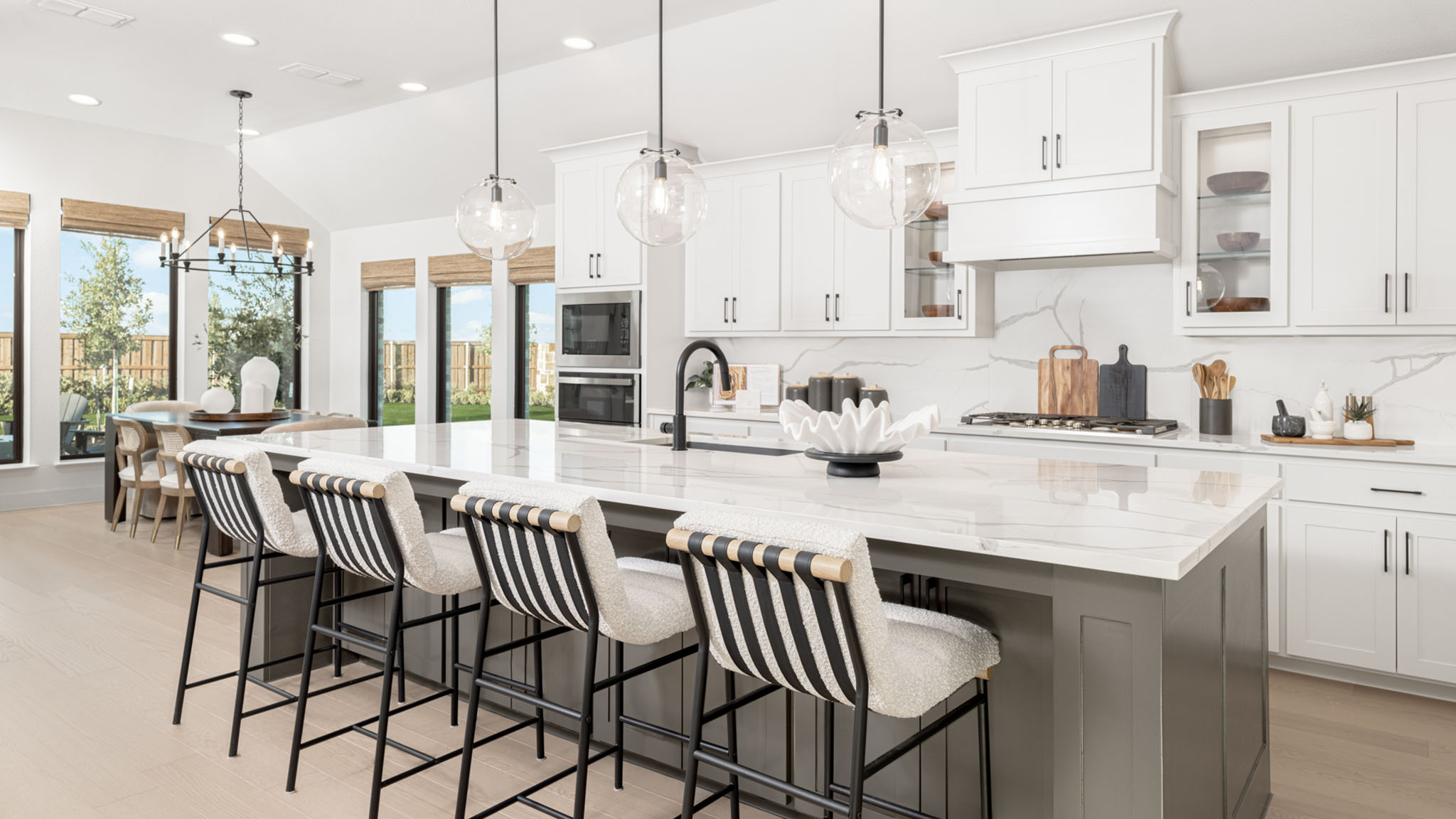 Kitchen with large island, glass globe pendants, and striped bar stools.