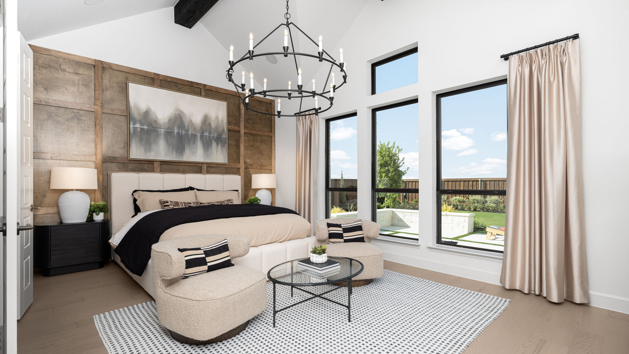 Bedroom with wood accent wall, round chandelier, and upholstered bed.