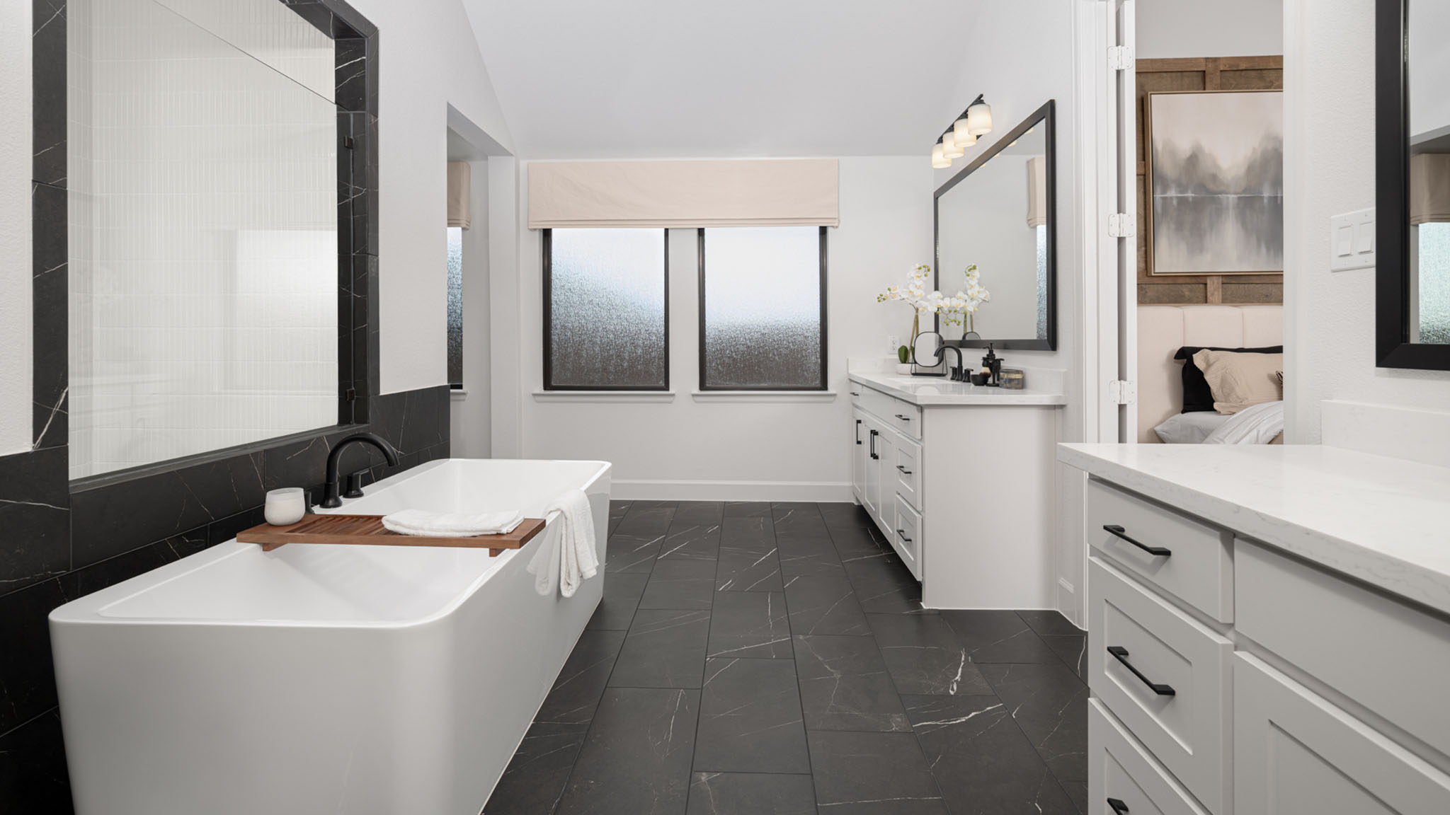 Bathroom with black marble floor tile, freestanding tub, and dual vanities.