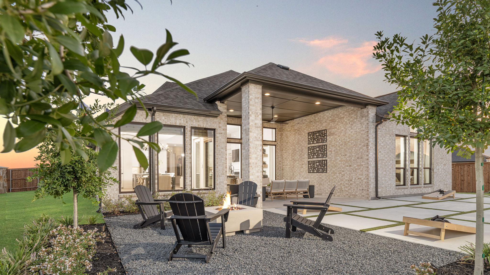 Covered outdoor patio with fire pit and Adirondack chairs at sunset.